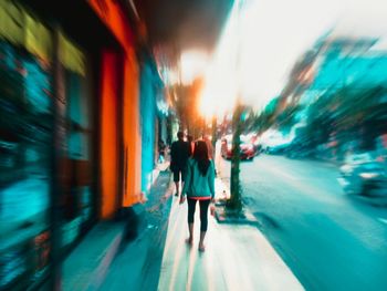 Rear view of people walking on street in city