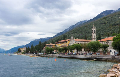 View of town by river against cloudy sky