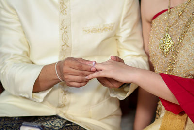 Midsection of wedding couple exchanging finger rings during ceremony