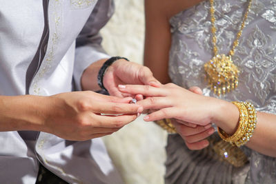 Midsection of wedding couple exchanging finger rings during ceremony