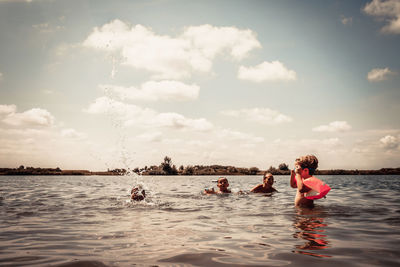 People enjoying in water against sky