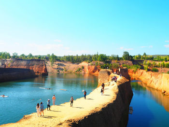 High angle view of people standing on walkway amidst river against sky during sunny day