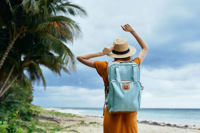 Rear view of man standing at beach against sky