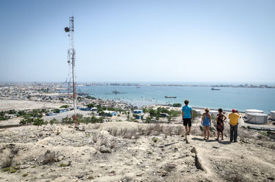 Rear view of friends standing against sea at beach