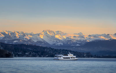 Scenic view of snowcapped mountains by sea against sky during sunset