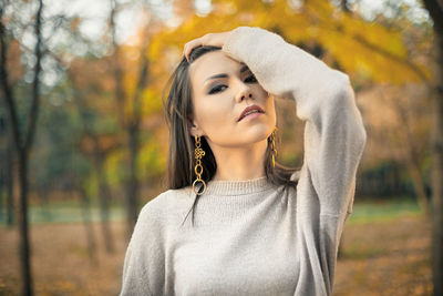 Young woman standing against trees