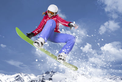 Low angle view of man jumping on mountain against sky