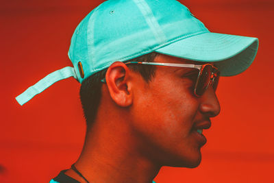 Portrait of man wearing sunglasses against red background