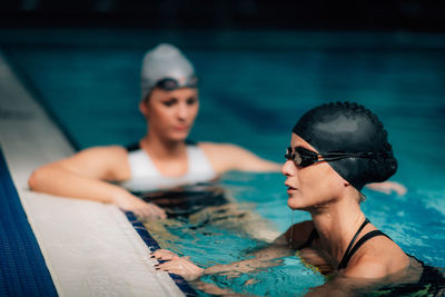 Young women resting, poolside, indoor pool. recreational swimming.