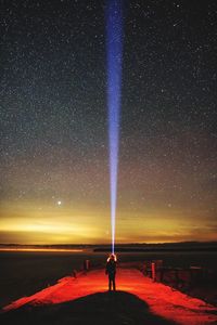 Woman standing on beach against star field at night