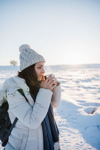 Side view of woman drinking coffee during winter