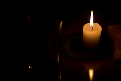 Close-up of lit candle in darkroom