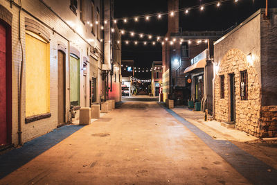 Illuminated street amidst buildings at night