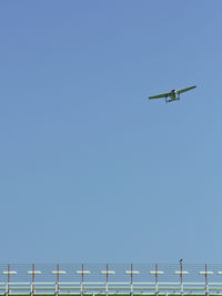 Low angle view of airplane flying against clear blue sky