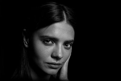 Close-up portrait of young woman over black background