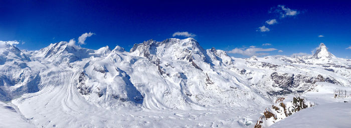 Scenic view of snowcapped mountains against blue sky