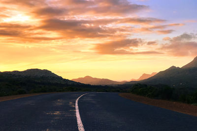 Empty road against sky during sunset