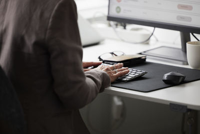 Mid section of woman in office using desktop pc