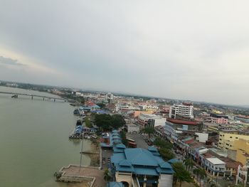 High angle view of town by sea against cloudy sky