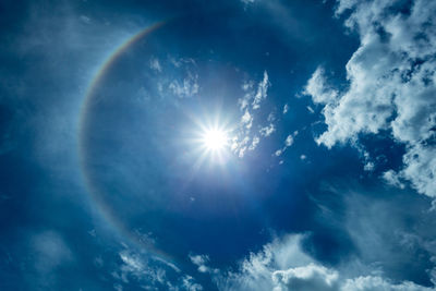 Low angle view of sunlight streaming through clouds