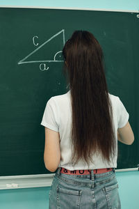 Asian high school girl solves geometry on the blackboard