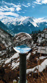 Close-up of ice on wooden post against sky