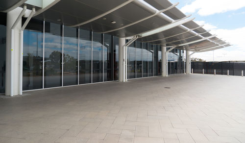 Empty footpath by buildings against sky