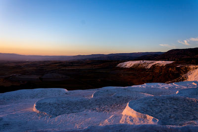 Scenic view of snowcapped mountains against clear sky during sunset