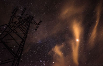 Low angle view of electricity pylon against sky at night