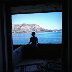 Man looking at sea seen through window