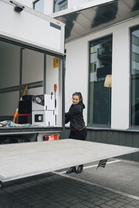 Portrait of woman standing against building