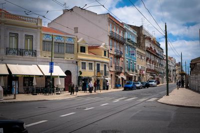 Road by buildings in city against sky