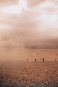 People on beach against sky during sunset