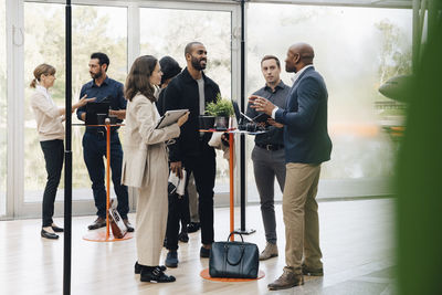 Male and female business professionals communicating while standing in office