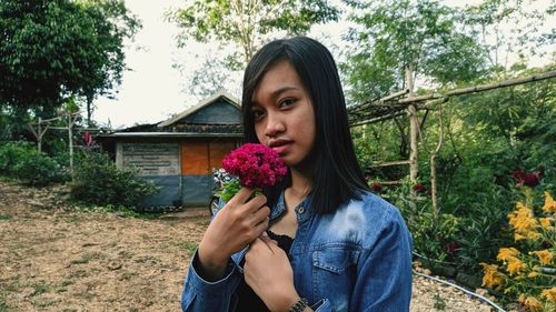 Portrait of beautiful young woman standing against plants