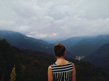 Rear view of woman standing on mountain against sky