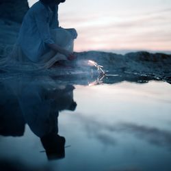 Reflection of woman holding sparklers