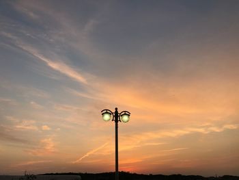 Silhouette street light against orange sky