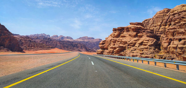 Road leading towards mountains against sky