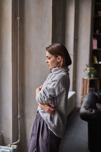 Woman looking through window at home