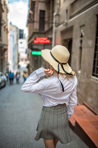 Rear view of woman wearing hat standing on street