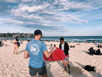 People photographing on beach against sky