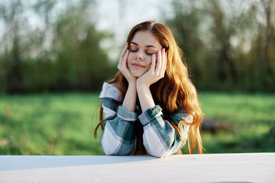 Portrait of young woman sitting on field