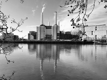 Buildings by river against sky in city