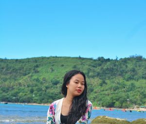 Portrait of beautiful woman standing against clear blue sky