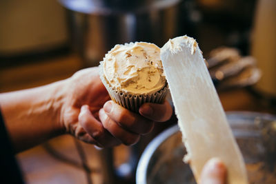 Close-up of person icing cupcake