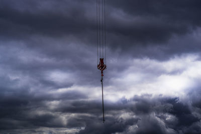 Low angle view of crane against cloudy sky