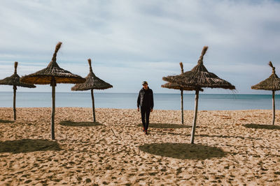 Full length of man walking on sand against sea at beach