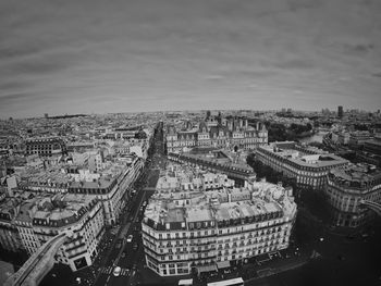 High angle view of city buildings against cloudy sky