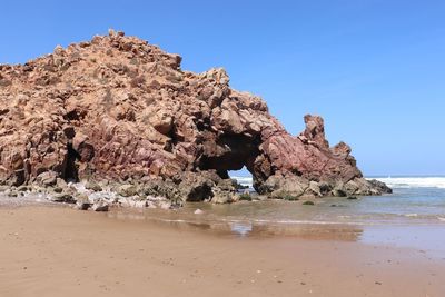 Rock formation on beach against clear blue sky